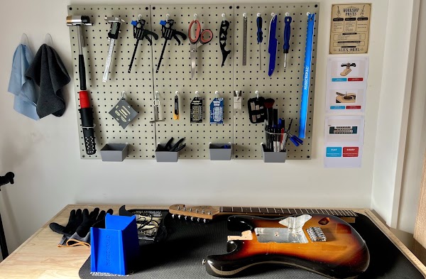 Electric guitar on Alex Orel’s workbench, with tools on the workshop wall